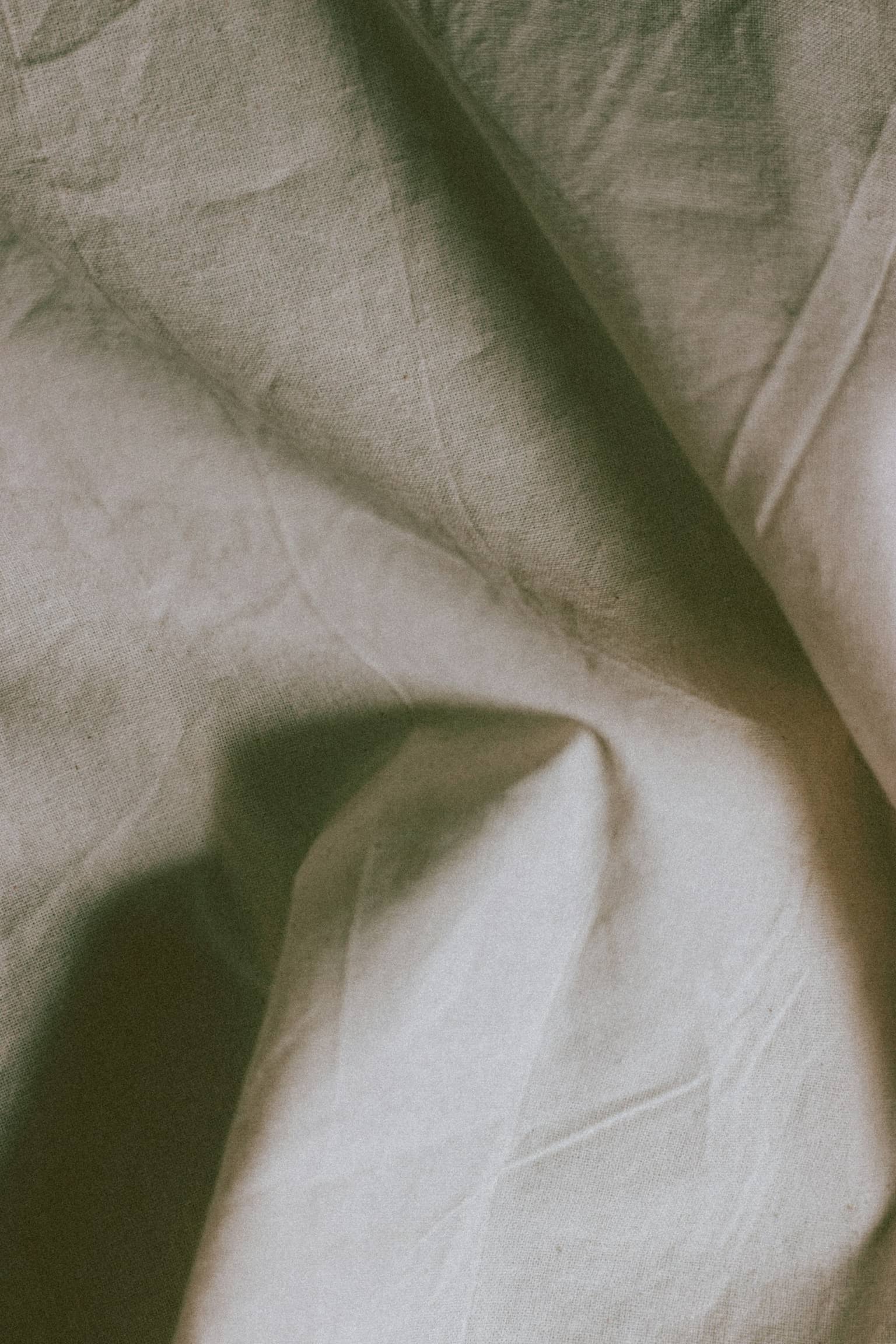 Folded linen on a worn wooden table, the colour of the rooms.