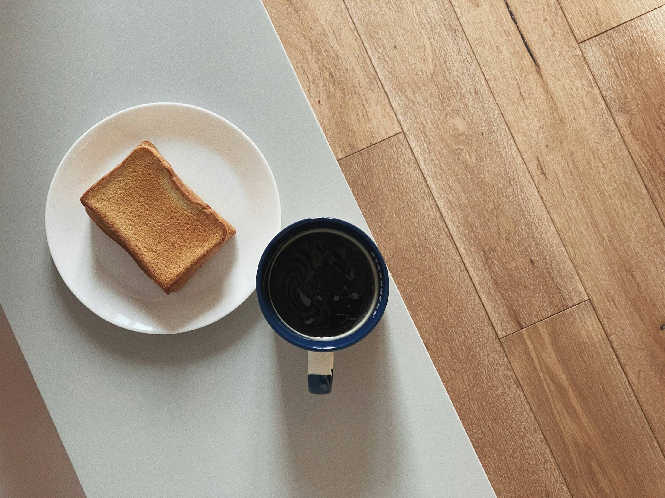 Breakfast in grey morning light: bread, coffee, the window beyond.