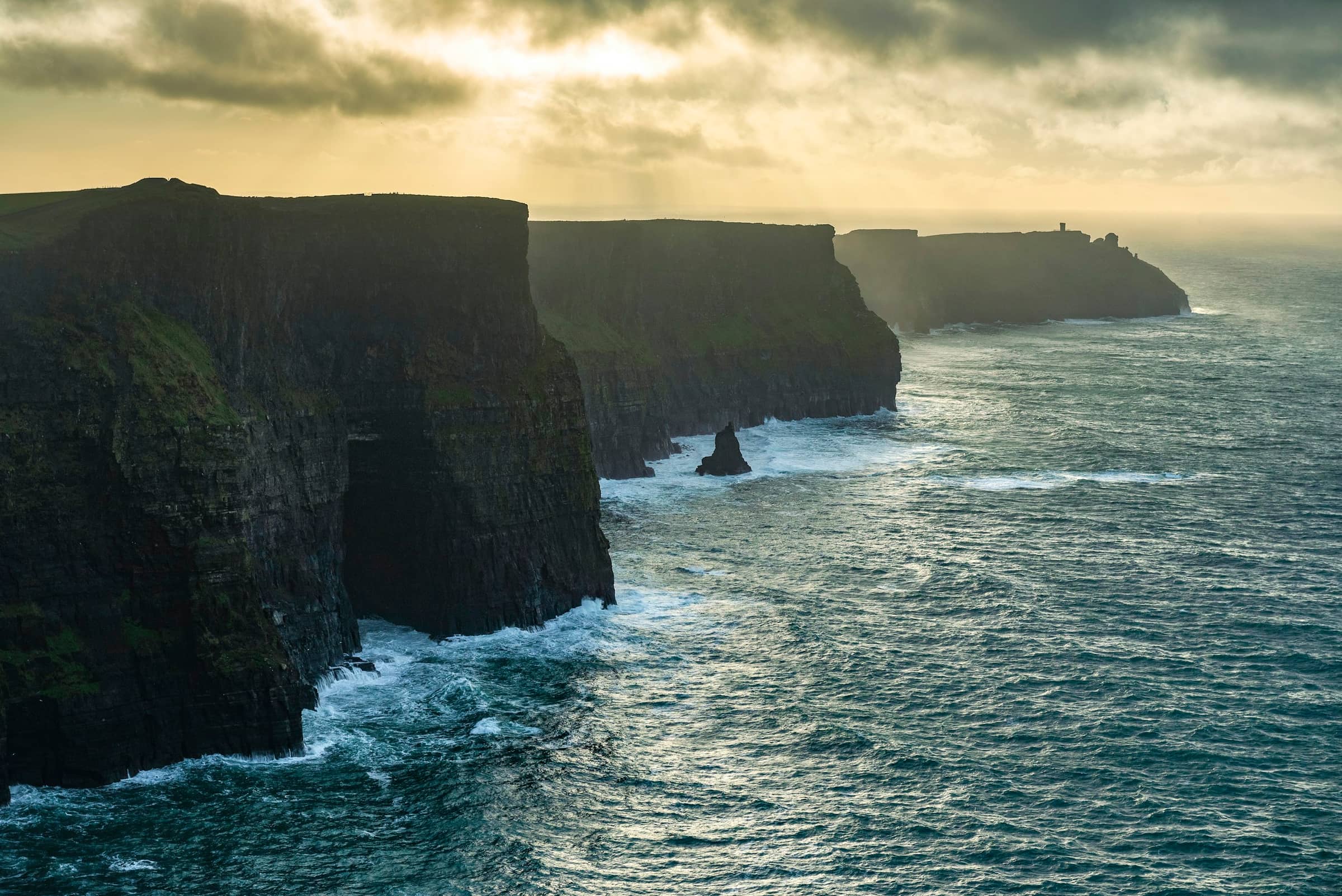 The Atlantic cliffs at dusk, the sun low and the sea working below.