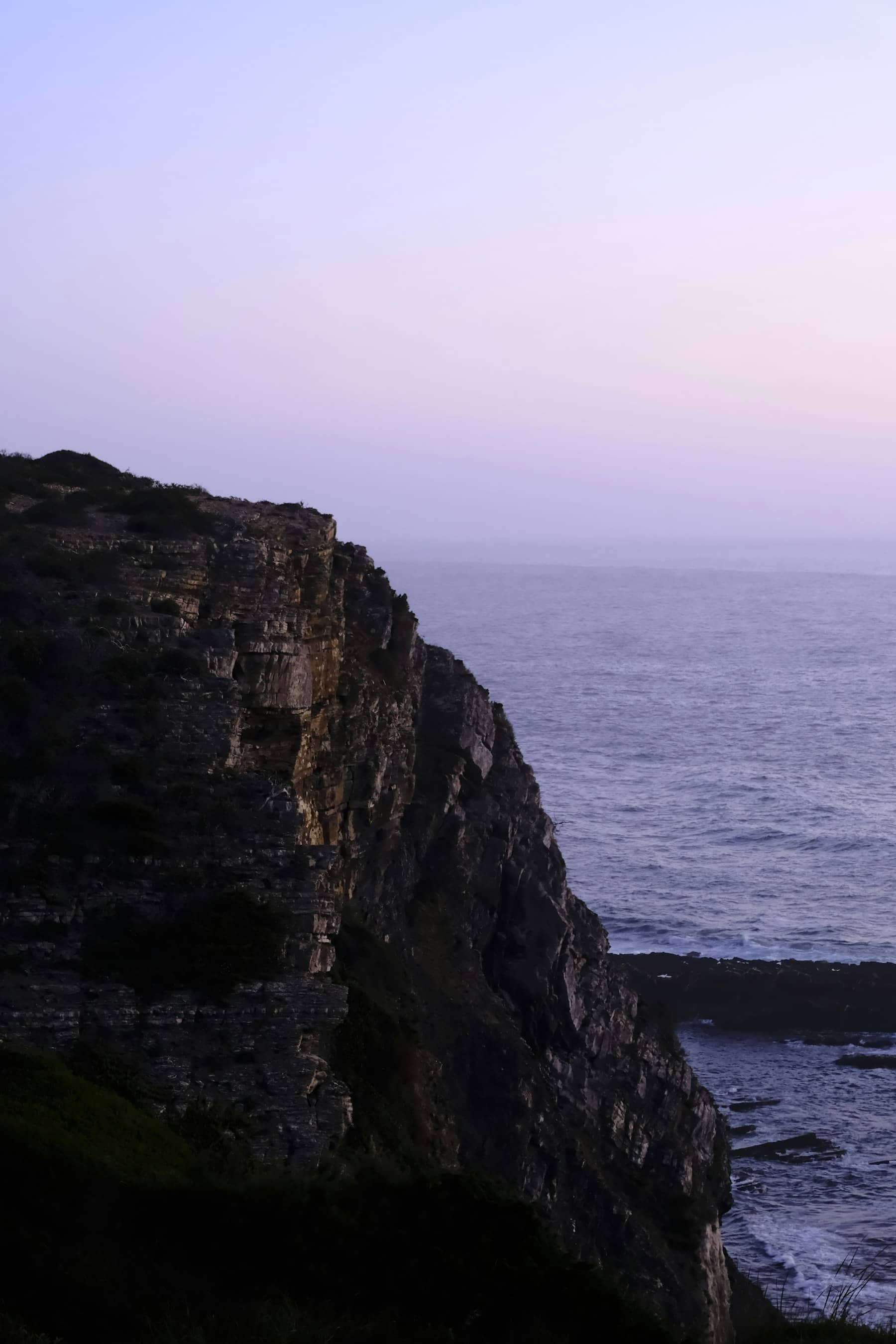 The cliff falling to the Atlantic at dusk, the sky going lilac.