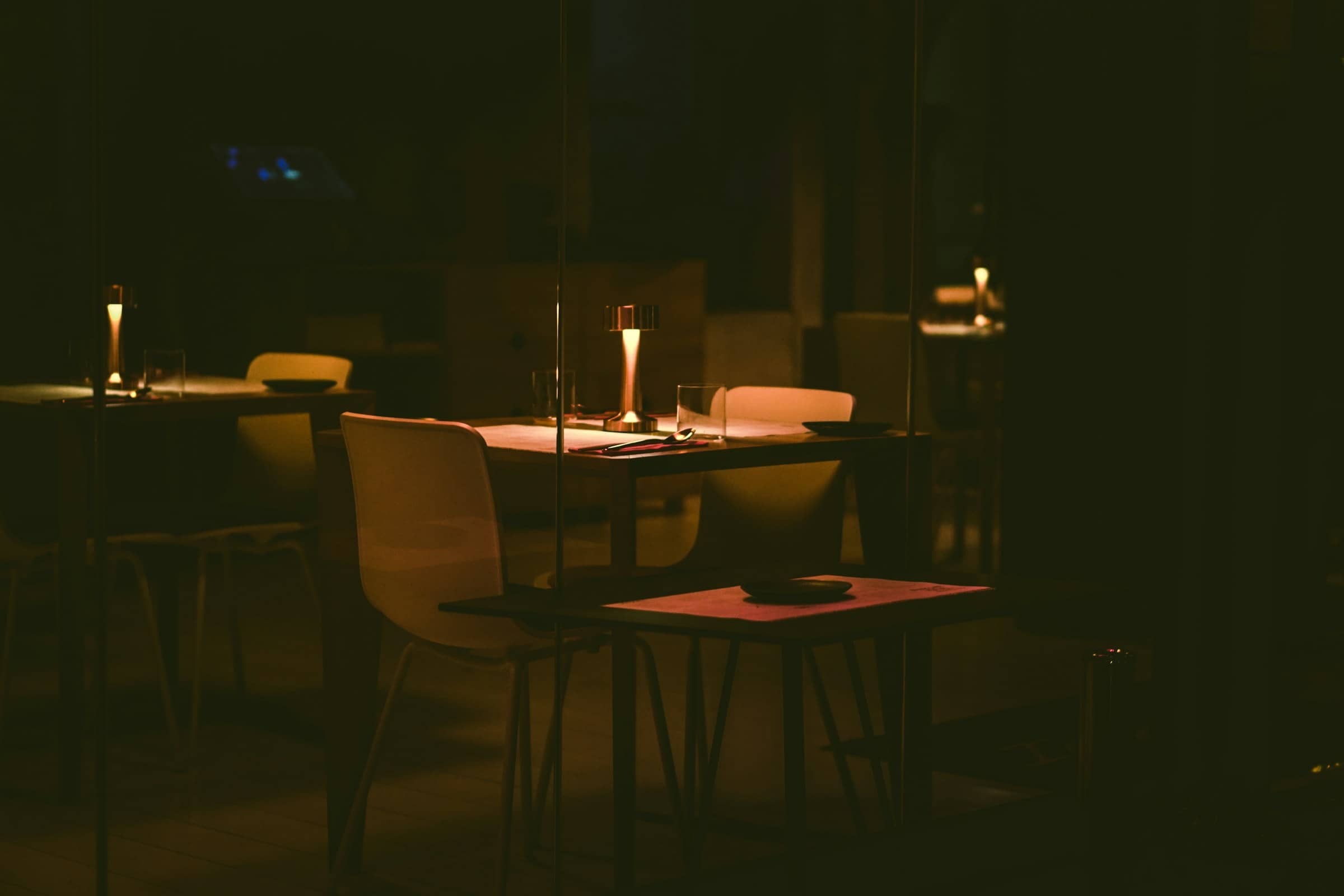 A single table set for supper by the window, the room dim and warm.